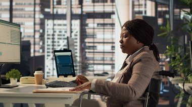 Kronik maluliyet sorunu olan kadın patron arşiv dosyalarını ve veri raporlarını inceleyerek kaynakları tahsis etmeden önce finansal bir plan hazırlıyor. Tekerlekli sandalyedeki iş kadını bilgileri inceliyor. Kamera A.