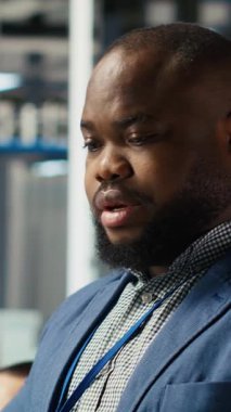 Dikey video Neşeli Fotovoltaik bitki uzmanı ofiste dayanıklılık ve performans alanında yenilikçi buluşlar üzerinde çalışıyor. Neşeli Afrikalı Amerikalı araştırmacı güneş panelleri için test materyalleri