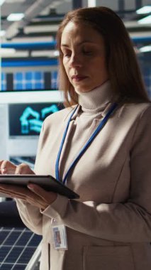 Dikey video Happy araştırmacısı güneş pili prototiplerini enerji üretimini optimize etmek için tablet kullanarak analiz ediyor. Neşeli güneş panelleri bitki uzmanı cihaz kullanarak yenilikçi üretim teknolojisi geliştiriyor