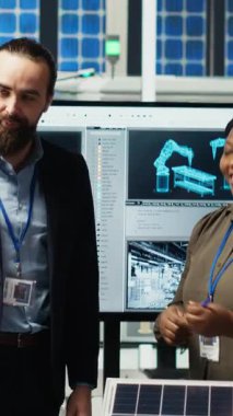 Fotovoltaik fabrika ofisindeki dikey video yöneticileri güneş teknolojisi raporlarını inceliyor. Hissedarlar, yeşil enerji üretiminde gelecekteki yatırım fırsatlarını tartışan B kamerasını okuyorlar