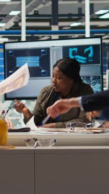 Dikey video endüstriyel fabrika yönetimi evrak ve şemaları inceliyor. Fabrika yöneticileri, otomasyon teknolojisinin üretim ve kamera A 'ya entegrasyonunu tartışmak üzere yatırımcılarla bir araya geldiler.