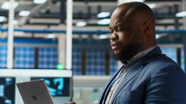 Neşeli fotovoltaik bitki uzmanı ofiste dayanıklılık ve performansta yenilikçi buluşlar üzerinde çalışıyor. Neşeli Afrikalı Amerikalı araştırmacı güneş panelleri için test materyalleri, kamera B