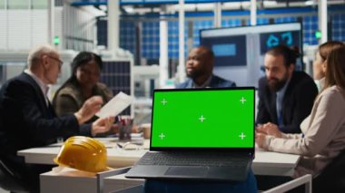 Fotovoltaik fabrikasının hissedarları yatırım stratejisini belirlemek için yeşil ekran dizüstü bilgisayardaki pazar eğilimlerini analiz ediyorlar. Yöneticiler krom anahtar defteri, genişleyen fabrika üretimi, kamera A verilerine bakarlar.