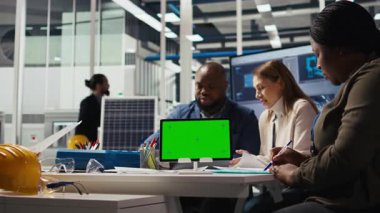 Montaj çizgileri üzerinde çalışırken fabrika mühendisi tökezliyor, yeşil ekran tableti kullanarak üretim planlarını inceliyor. Uzmanlar, endüstriyel fabrika yapılandırmalarını modelleme cihazı, kamera A kullanarak özetliyor