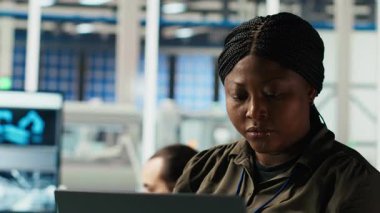 Araştırmacının portresi güneş pili prototiplerini enerji üretimini optimize etmek için dizüstü bilgisayar kullanarak analiz eder. Gülümseyen Afro-Amerikan güneş panelleri yenilikçi üretim teknolojisi geliştiren bitki uzmanları, kamera B