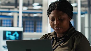 Fabrikada gülümseyen mühendisin portresi parametreleri kontrol etmek ve güneş panelinin dayanıklılığını artırmak için dizüstü bilgisayar kullanır. Mutlu Afrikalı Amerikalı araştırmacı verimli sürdürülebilir enerji çözümleri geliştiriyor, kamera B
