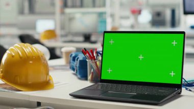 Fotovoltaik fabrika sistemi parametrelerini ayarlamak için kullanılan yeşil ekran laptop. Ofisteki Mockup defteri güneş paneli üretim tesisinde enerji arzını optimize etmek için kullanılır