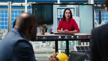 Ofisteki yöneticiler internet video görüşmesi sırasında güneş teknolojisi raporlarını inceliyorlar. Uzak telekonferans toplantısındaki hissedarlar yeşil enerji üretimindeki yatırım fırsatlarını tartışıyorlar, kamera B
