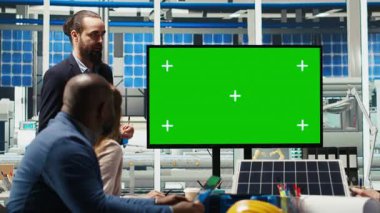 Fotovoltaik bitki araştırmacıları toplantı yapıyor, yeşil ekran monitörüne bakıyor, enerji üretimini değerlendiriyor. Uzmanlar fabrika ekipman enerji çıktısını optimize ederek, model ekran, kamera B 'ye bakıyorlar