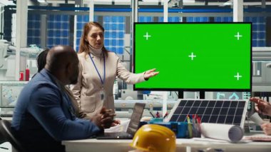 Fabrika mühendisleri yeşil ekran monitörü önünde iş toplantısında montaj hatlarının şemalarına bakarlar. Uzmanlar endüstriyel fabrika yapılandırmaları üzerinde model ekran, kamera B kullanarak çalışırlar