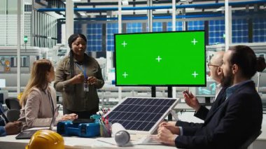 Yönetim yöneticileri, güneş paneli üretimi için otomasyon stratejilerine yeşil ekran monitöründen bakıyorlar. Fabrikadaki işadamları finansal yatırımlar yapıyor. Model ekrana, kamera A 'ya bakıyorlar.