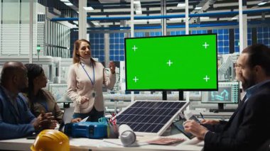 Fabrika mühendisleri yeşil ekran monitörü önünde iş toplantısında montaj hatlarının şemalarına bakarlar. Uzmanlar endüstriyel fabrika yapılandırmaları üzerinde model ekran, kamera A kullanarak çalışırlar