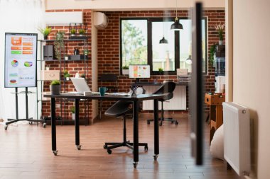 Çalışanlar için hazırlanmış dijital cihazları ve mobilyaları olan boş tuğla duvar odası. Girişim şirketi çalışma alanı bilgisayarlarla ve modern ofis malzemeleriyle iyi düzenlenmiştir..