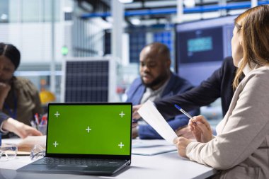 Üretim fabrikasındaki iş arkadaşları, yenilikçi üretim stratejilerini analiz ederek, dizüstü bilgisayardaki araştırma ve geliştirme verilerine göz atıyorlar. İş adamları yeşil ekran dizüstü bilgisayar kullanarak beyin fırtınası yenilikleri yapıyor