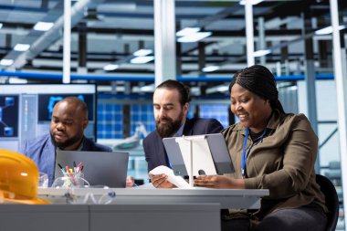 İş adamları iş yatırım stratejisini değerlendirmek için elektronik verileri inceliyor. Fabrika yöneticileri ve sanayi fabrikasındaki hissedarlar belgeleri incelemek için aygıtlar kullanıyorlar