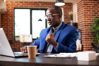 Genç girişimci masasına oturmuş, yumruğunu kaldırmış, iş projesinin tamamlanışını kutluyordu. Kara işadamı laptopta e-posta okuyor. Başarılı piyasa stratejisinde iyi haberler için heyecanlı..