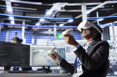 Robot kolların montaj hatlarına güneş panelleri yerleştirme performansını izlemek için VR kulaklık kullanan fotovoltaik fabrika işçisi. Sanal gerçeklik ekipmanları kullanarak güneş santrali makinelerini denetleme uzmanı