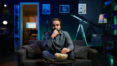 Kafası karışık bir adam yayın servisiyle ilgili kafa karıştırıcı bir film izlerken patlamış mısır yiyor, işten izin almanın keyfini çıkarıyor. Abur cubur yiyen kişi, TV 'de yayınlanan filme karışık bir çerçeve ile bakıyor, kamera B