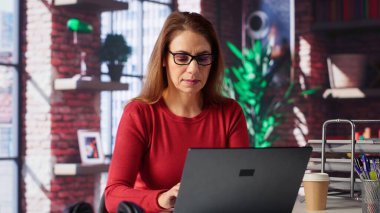 Freelancer araştırmasını, yeni bir proje için bilgi toplamak amacıyla evde makaleler ve veri odaklı kağıtlar okuyarak yapıyor. Kadın, el yazısı notlarla birden fazla iş yapıyor ve dosyaları inceliyor. Kamera A.