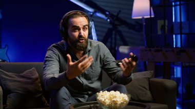 Oyun oynarken TV ekranına bakan, oyun konsolundaki mesajdan oyun alan bir adam. Oyuncu, online esports yarışmasında rakip oyuncular tarafından mağlup edildikten sonra üzgün. Kamera A