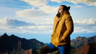 Gezgin, yüksek rakımlı yabanda tek başına duruyor nefes kesen manzaraya hayran, temiz havanın ve çarpıcı dağ manzarasının tadını çıkarıyor. Huzurlu atmosfer farkındalığa ilham verir. Kamera B.