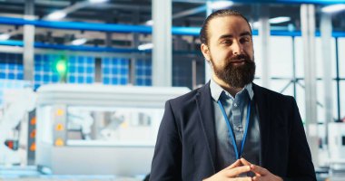 Güneş paneli fabrikası uzmanı, gelişmiş üretim ekipmanları ve yenilenebilir enerji çözümlerinin altını çizerek turneye çıkıyor. Endüstriyel tesislerdeki adam yeşil enerji üretim sürecini sunuyor, kamera B