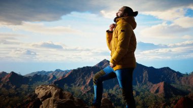 Kararlı gezgin, panoramik manzaranın macera ve kişisel gelişimi temsil ettiği bir dağ zirvesinin yalnızlığının tadını çıkarıyor. Yürüyüşçü rüzgarlı dağın tepesinde üşüyor. Kamera A.