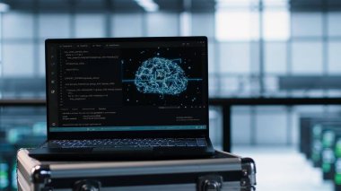 Bulanık arka planda veri merkezi mühendislerinin önünde suni zeka güdümlü yönetim araçları yerleştiren dizüstü bilgisayar. Sunucu kümelerini denetlemek için kullanılan yapay zeka kullanan defter, kamera A, kapat