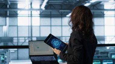 Veri merkezindeki teknisyen güç yönetimi ayarlarını ayarlamak için yapay zeka teknolojisini tablette kullanıyor. Sunucu odasındaki mühendis, yapay zeka ve kamera A kullanarak kaynak kullanımını optimize ediyor.