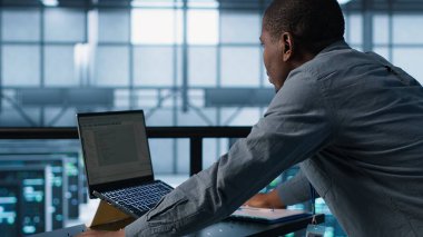 Veri merkezinde dizüstü bilgisayarda teknisyen kodlaması, sunucu viralizasyonunu yönetmek, ağ protokollerini düzenlemek. Defterde sunucu çiftliği çalışanı programlaması, gelişmiş güvenlik önlemleri, kamera A