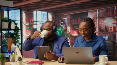 Siyahi kadın, partneri yanında müzik dinlerken çalışıyor, evde birlikte geçirdikleri zamanın tadını çıkarıyor. Freelancer dizüstü bilgisayardaki günlük işlerini çözüyor, erkek arkadaşı da internete kayıyor. Kamera A.