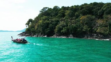 Kıyı kayalıkları olan tropikal bir cennetteki bir motorlu teknenin havadan görünüşü, kıyı şeridi yakınlarındaki turkuaz suları keşfeden bir teknenin yer aldığı Tayland deniz manzarasını hayrete düşürüyor. Tayland 'da egzotik lagün körfezi.
