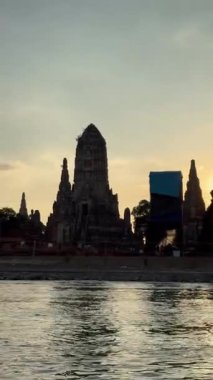 Dikey Tayland Videosu, Kasım 2024 - Wat Chaiwatthanaram Ayutthaya tapınağı nehir teknesinden, altın gün batımının altında antik tuğla kuleler. Geleneksel miras, kültür ve mimari.