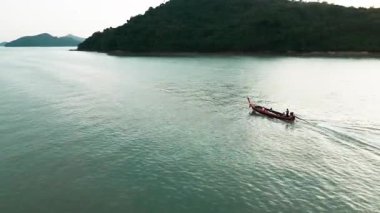 Tayland yakınlarındaki turkuaz bir göldeki ahşap teknelerin insansız hava aracı görüntüleri. Cennet sahili, çarpıcı mavi bir körfezdeki motorlu tekneleri gösteriyor. Tropik kayalıklar, palmiye ağaçları ve küçük adalar.