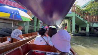 Tayland, Kasım 2024 - Bangkok 'ta yüzen bir pazarı keşfeden turistler, Tayland mutfağıyla dolu tekneler. Kanaldaki yerel üretim eşsiz bir deneyim sunuyor.