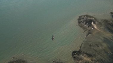 Tayland koyunda yelkenli tekneleri olan tropikal bir adanın havadan görünüşü sakin bir gölde sürüklenen yelkenli teknelerinin olduğu çarpıcı bir seyahat rotası. Palmiye ağaçları, altın plajlar ve turkuaz bir okyanus..