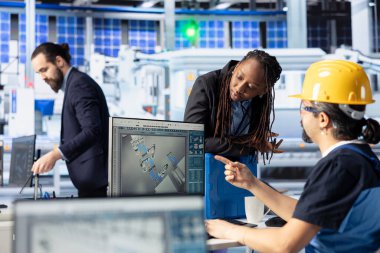 Photovoltaics tesis lideri üretim üretimini arttırmak için teknisyen tarafından yapılan çalışmaları denetliyor. Güneş panelleri fabrika mühendisi Afro-Amerikan yöneticisinin sistem hatalarını tanımladığını gösteriyor