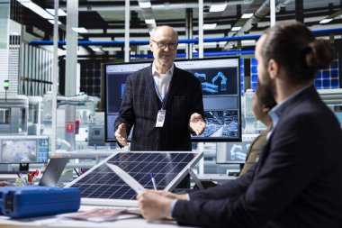 Photovoltaics fabrikasının kıdemli müdürü sistemleri geliştirmek için mühendislerden güncellemeler alıyor. Yaşlı güneş panelleri fabrika yönetimi yöneticisi, kesintileri azaltmak için atılacak adımları tartışıyor