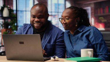 Afrika kökenli Amerikalı bir çift, internet yayını dinlemek için kulaklık kullanıyor ya da bir web platformunda online tartışmayı dinliyorlardı. Serbest çalışan erkek ve kadın masada vakit geçiriyorlar. Kamera B.