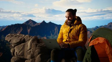Genç kaşif dağın tepesinde çalışmaya devam ediyor. Her yerde internet var. Tepe zirvesinde küresel bağlantının ve verimliliğin tadını çıkarıyor. Yürüyüş sırasında yüksek hızda güçlü sinyal. Kamera A.