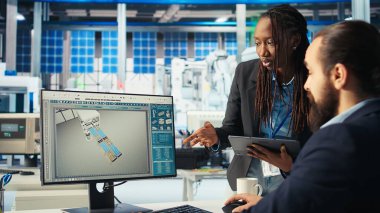 Fotovoltaik fabrikası müdürü ve iş arkadaşı beyin fırtınası, güç üretimini maksimuma çıkarmak için sistem parametrelerini ayarlıyor. Adam iş arkadaşıyla konuşuyor, güneş paneli santralinde enerji kaynağını optimize ediyor, kamera A