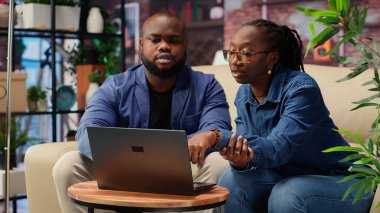 Afrikalı Amerikalı çift, iş eğilimlerini araştırmak ve çevrimiçi bir markayı yönetmek için bir dizüstü bilgisayar kullanarak bağımsız çalışma projesi üzerinde çalışıyor. Uzaktan kumandalı başarılı kariyer gelişimi. Kamera B.