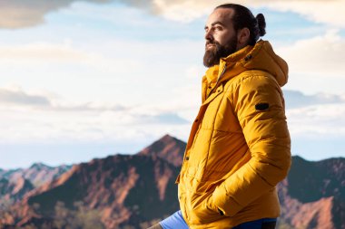 Sıcak giysili maceraperest, vahşi doğanın huzurunu, panoramik dağ manzarasını ve açık gökyüzünü sever. Rahatlamak için mükemmel bir ortam yaratır. Soğuk rüzgarlar yokuş yukarı.