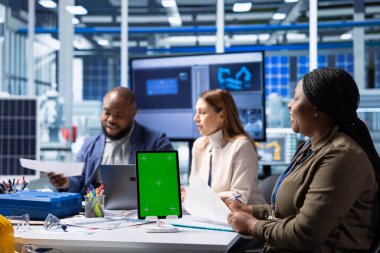 Fotovoltaik fabrikası teknisyenleri güneş panelleri verimliliğini arttırmak için izole ekran tableti kullanıyorlar. Güneş panelleri, sürdürülebilir güneş çözümlerini model kullanarak araştıran fabrika iş arkadaşları üretiyor.