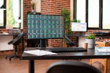 Piyasa stratejisi araştırmalarına odaklanan boş bir ofisteki finansal hisse verilerinin dijital görüntüsü. Tuğla duvar odasında kullanılmaya hazır iş analiz araçlarını gösteren masaüstü monitörü.