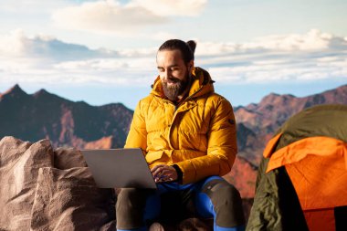 Genç kaşif dağın tepesinde çalışmaya devam ediyor. Her yerde internet var. Tepe zirvesinde küresel bağlantının ve verimliliğin tadını çıkarıyor. Yürüyüş sırasında yüksek hız güçlü sinyal.