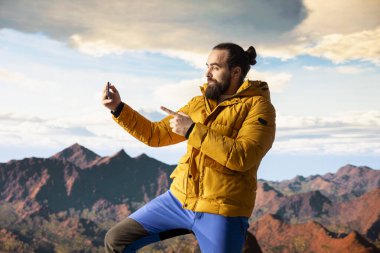 Neşeli yürüyüşçü bir dağ zirvesine tırmanıyor ve sosyal medya için bir video bloğu çekiyor, çevrimiçi izleyicisi için içerik yaratıyor. Genç nüfuzlu gezgin İnternet 'ten canlı yayın yapıyor..