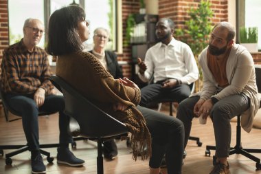 Tuğla duvar odasında oturan genç ve emekli bireyler terapi seanslarında ruh sağlığı hakkında tartışıyorlar. Çeşitli gruplar A.A. toplantısında beyaz kadının duygularını dinliyorlar.