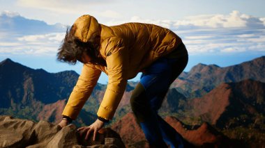 Şiddetli rüzgarla savaşan ve daha iyi bir telefon sinyali arayan genç yürüyüşçü, dağın tepesindeki akıllı telefon tarafından dikkatsiz davranıyordu. Manzaralı bir zirvenin sarp kayalıklarında yuvarlanarak. Kamera B.