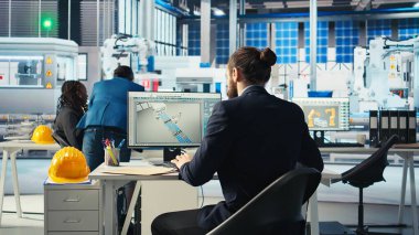 Photovoltaics fabrikası uzmanı robot kollarının montaj hatlarına güneş panelleri yerleştirmesini sağlayacak belgelerin özelliklerini inceliyor. Uzman güneş santrali makine evraklarını okudu